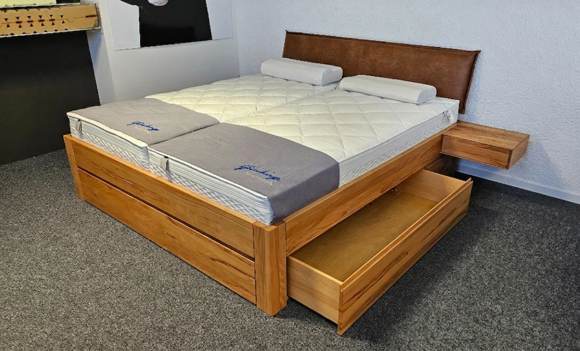 Schukastenbett aus Massivholz mit braunem Lederkopfteil und offener Schublade